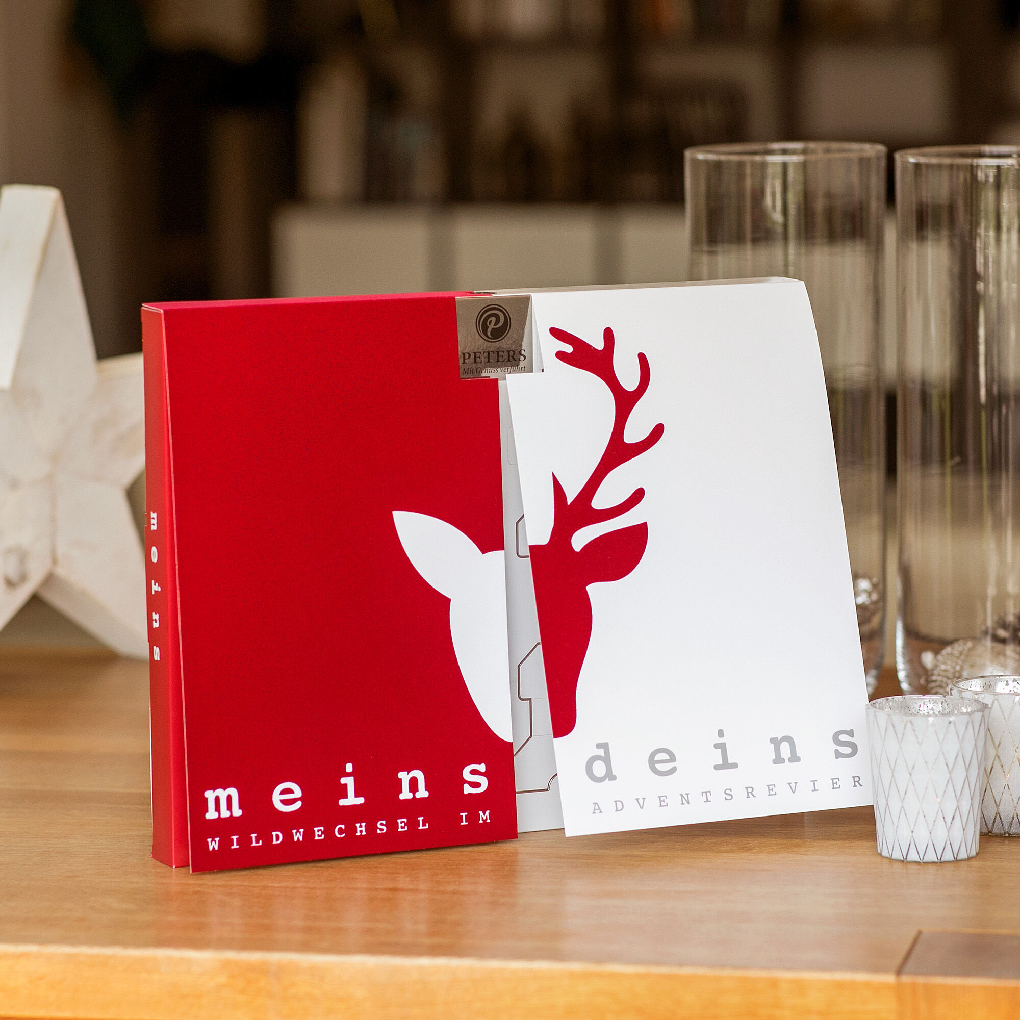 PETERS Adventskalender „Meins & Deins“ auf gedecktem Tisch mit weißen Servietten