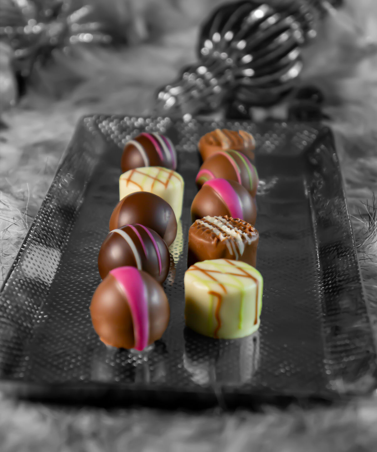 Verzierte Weihnachtspralinen stehen in zwei Reihen auf einem Teller